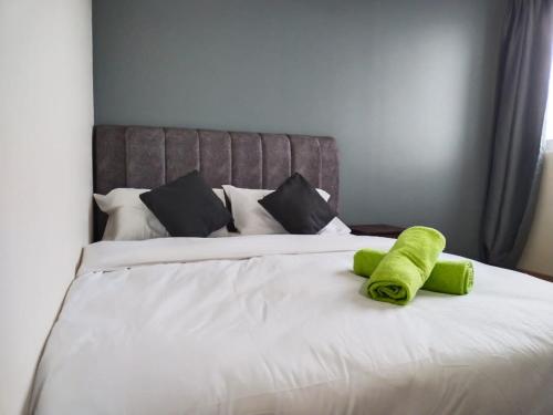 ein grünes Handtuch auf einem weißen Bett in der Unterkunft 3 bedrooms big house saville cheras MRT with balcony in Cheras
