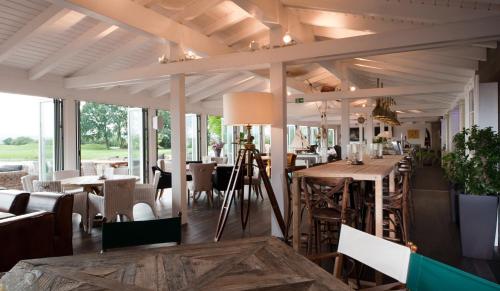 uma sala de jantar com mesas, cadeiras e janelas em Hotel Diamond Country Club em Atzenbrugg