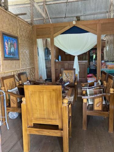 a room with a bunch of wooden chairs and tables at Areef Homestay Kaledupa in Kaledupa