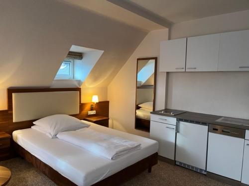 ein Schlafzimmer mit einem weißen Bett und einer Küche in der Unterkunft Boardinghouse am Wall in Salzgitter-Bad