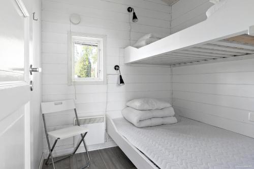 a small white room with a bed and a chair at First Camp Mörudden-Karlstad in Gunnarskär