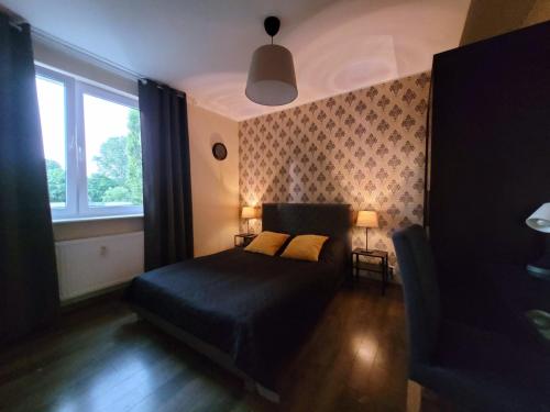 a bedroom with a black bed and a window at Gdansk - nad morzem in Gdańsk