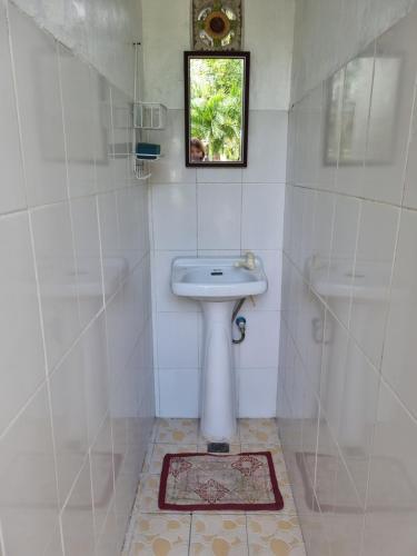 ein weißes Badezimmer mit einem Waschbecken und einem Spiegel in der Unterkunft Southpoint Hostel in Moalboal
