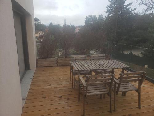 une terrasse en bois avec des tables et des chaises sur un balcon dans l'établissement Six-fours les plages, à Six-Fours-les-Plages