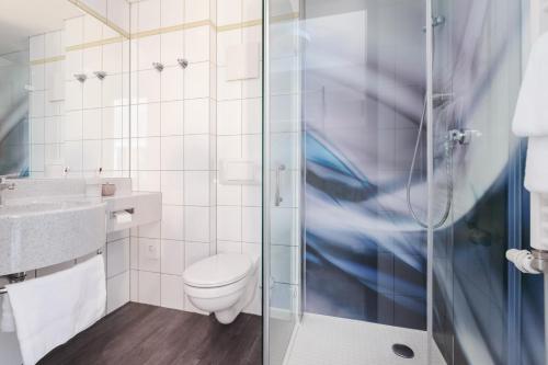 uma casa de banho com um WC e uma cabina de duche em vidro. em Select Hotel Elmshorn em Elmshorn
