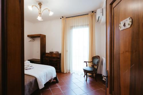 um quarto com uma cama, uma cadeira e uma janela em Acetaia Malagoli Daniele e B&B em Castelfranco Emilia