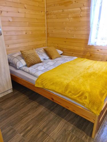 a bed in a room with a wooden wall at DOMKI POD ZIELONYM WZGÓRZEM in Kudowa-Zdrój