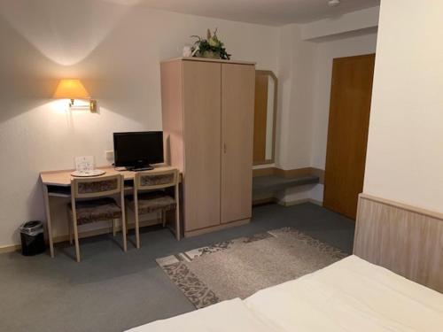 a bedroom with a desk with a computer and a cabinet at Zum Flößer in Neckartenzlingen