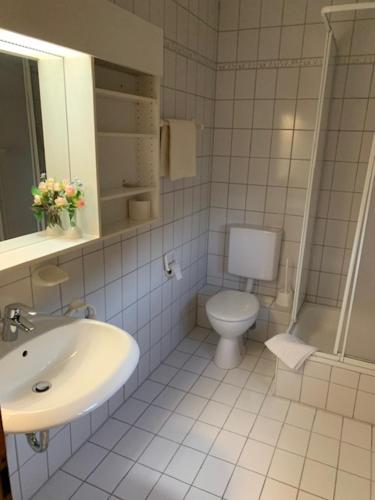 a white bathroom with a toilet and a sink at Zum Flößer in Neckartenzlingen