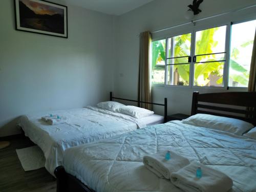 two beds in a bedroom with towels on them at Open Kitchen Chiang Rai in Chiang Rai