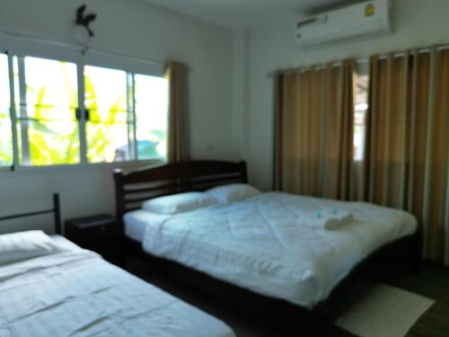 a bedroom with two beds and two windows at Open Kitchen Chiang Rai in Chiang Rai