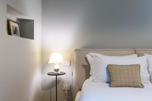 uma cama branca com uma almofada e um candeeiro em Contempora Apartments - Visconti di Modrone em Milão