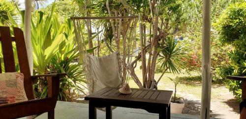 a porch with a table and a chair and trees at Moana Breeze Rangiroa - Rental car included - Air conditioning - WI-Fi in Tiputa