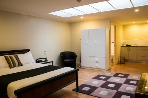 a bedroom with a bed and a cabinet and a chair at merseybank apartments in Devonport