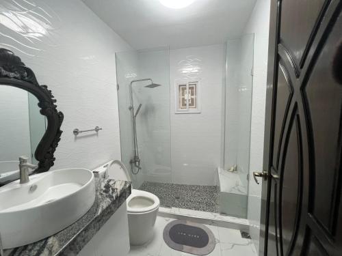 a white bathroom with a sink and a shower at Pike Guest House in Dagupan