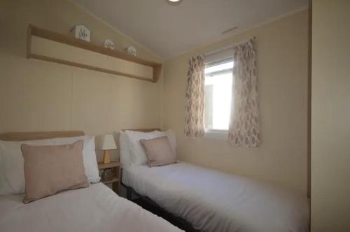 2 camas en una habitación con ventana en Oyster Etchingham SEAVIEW, en Whitstable