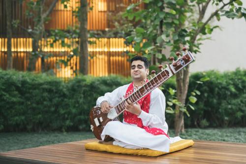 a man sitting on a table playing a guitar at Six Senses Vana - A Wellness Retreat in Dehradun