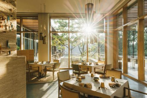 restauracja ze stołami i krzesłami oraz dużym oknem w obiekcie Six Senses Vana - A Wellness Retreat w mieście Dehradun