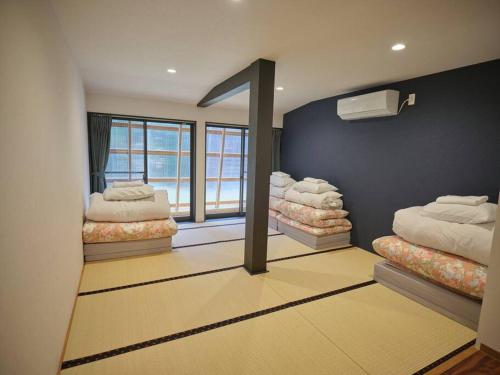 Habitación con 3 camas en una habitación en WAY SHIRAKAWAGO - Private, Free Parking and Newly Opened 2022 WAY SHIRAKAWAGO, en Shirakawa