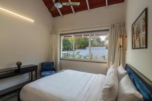 a bedroom with a bed and a window at SaffronStays Mariposa by the River Sol, Karjat in Karjat