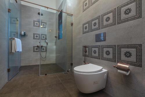 a bathroom with a toilet and a glass shower at SaffronStays Mariposa by the River Sol, Karjat in Karjat