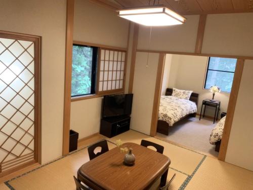 1 dormitorio y sala de estar con mesa y 1 cama. en 一棟貸切 森のお風呂とアウトドアサウナ 日光雪月花 en Nikko