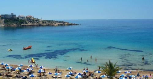 a group of people on a beach with umbrellas at Ascos Coral Beach Hotel in Coral Bay