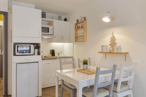 une cuisine avec une table et un réfrigérateur blanc dans l'établissement Rivière 210 - Happy Rentals, à Chamonix-Mont-Blanc
