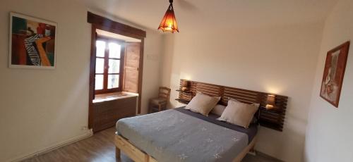 1 dormitorio con 1 cama con cabecero de madera y ventana en Chambres d'hôtes La Prévôté - Ancien couvent contre la Cathédrale, en Le Puy en Velay