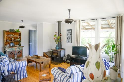 a living room with a couch and a tv at Bush & Bay Cottage in Erowal Bay