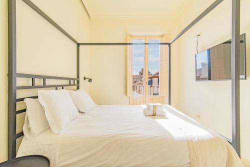 a white bed in a room with a window at Mosaiko Homes Catedral Granada in Granada