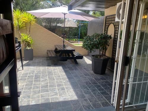 a patio with a bench and an umbrella at Tula@159 in Bloemfontein
