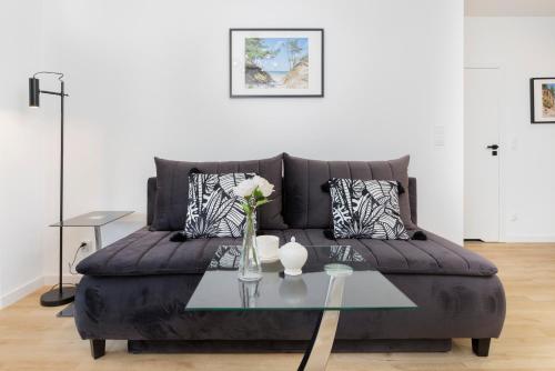 a living room with a black couch with a glass table at Plac Unii Apartment Gdynia by Renters in Gdynia