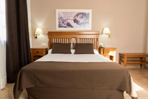 a bedroom with a large bed and two tables at Carlos I Toledo in Yuncos