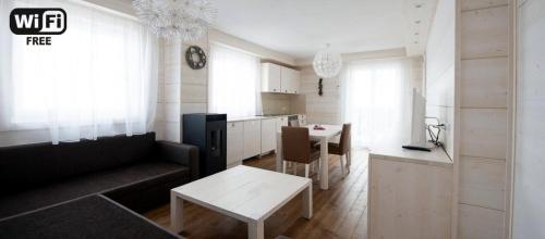 ein Wohnzimmer mit einem Sofa und einem Tisch sowie eine Küche in der Unterkunft Zoncolan Laugiane in Sùtrio