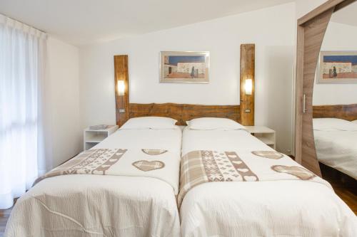 two beds in a hotel room with white sheets at Hotel Biancospino in Lanzada
