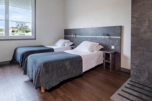 a bedroom with two beds and a window at Hôtel de la Gare in Surgères