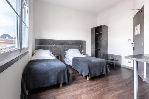 a bedroom with two beds and a window at Hôtel de la Gare in Surgères