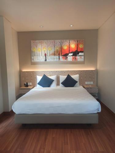 a bedroom with a large white bed with blue pillows at Dwijaya House of Pakubuwono in Jakarta