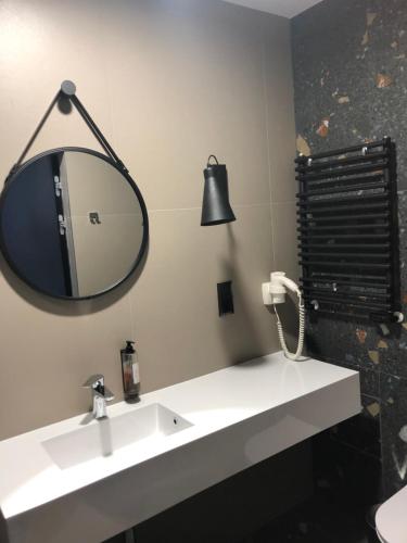 a bathroom with a sink and a mirror at Apartament Biała Perła in Sienna