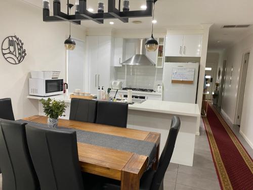 uma cozinha e sala de jantar com uma mesa de madeira e cadeiras em Comfy nest 4 bed room family house em Melton South