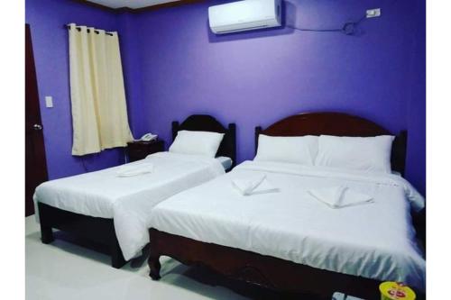 2 camas num quarto com uma parede roxa em OYO 926 Casa Venicia Caticlan em Boracay