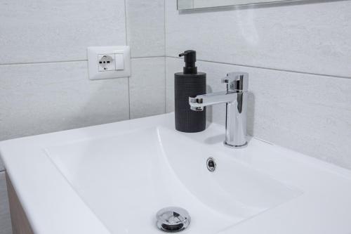 a white bathroom sink with a black soap bottle on it at Hotel Biancospino in Lanzada