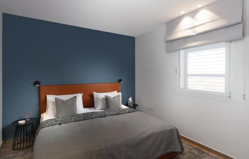 a bedroom with a bed with blue walls and a window at AMALON Boutique Apartments in Jerusalem