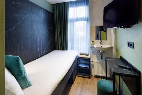 a small room with a bed and a sink at Ciao Papa Hotel Amsterdam Central Station in Amsterdam