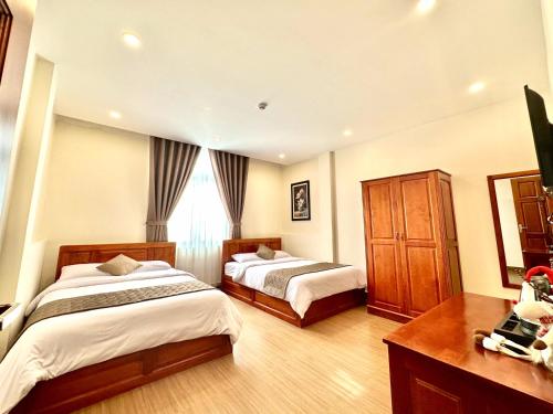 a bedroom with two beds and a dresser at Nam Xuan Premium Hotel in Da Lat