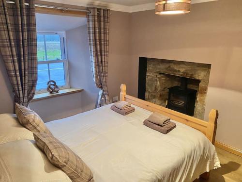 um quarto com uma cama em frente a uma lareira em The Old Schoolhouse Lochearnhead em Lochearnhead