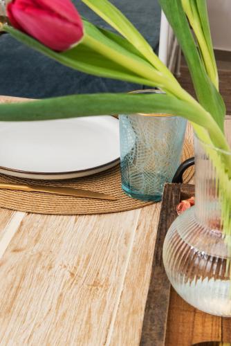 a table with a vase with a red tulip in a glass at Athena Luxury Studios in Athens