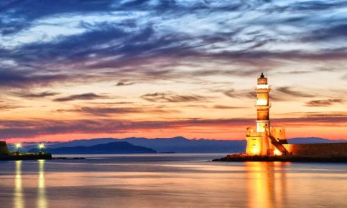 a lighthouse sitting in the water at sunset at Cretan Kera Villa Heated Pool in Kerá