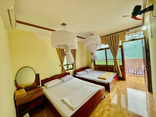 a bedroom with two beds and a mirror and chandeliers at Ba Be Lake View Homestay in An Ma